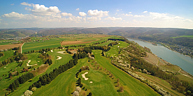 Weitläufiger Golfplatz mit grünen Fairways und Fluss im Hintergrund.