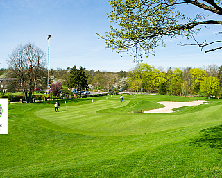 Weite Ansicht eines Golfplatzes mit Spielern und Bunkern.