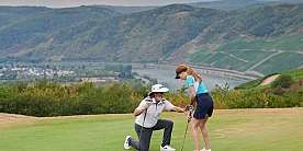 Ein Trainer zeigt einem jungen Mädchen die richtige Golftechnik.